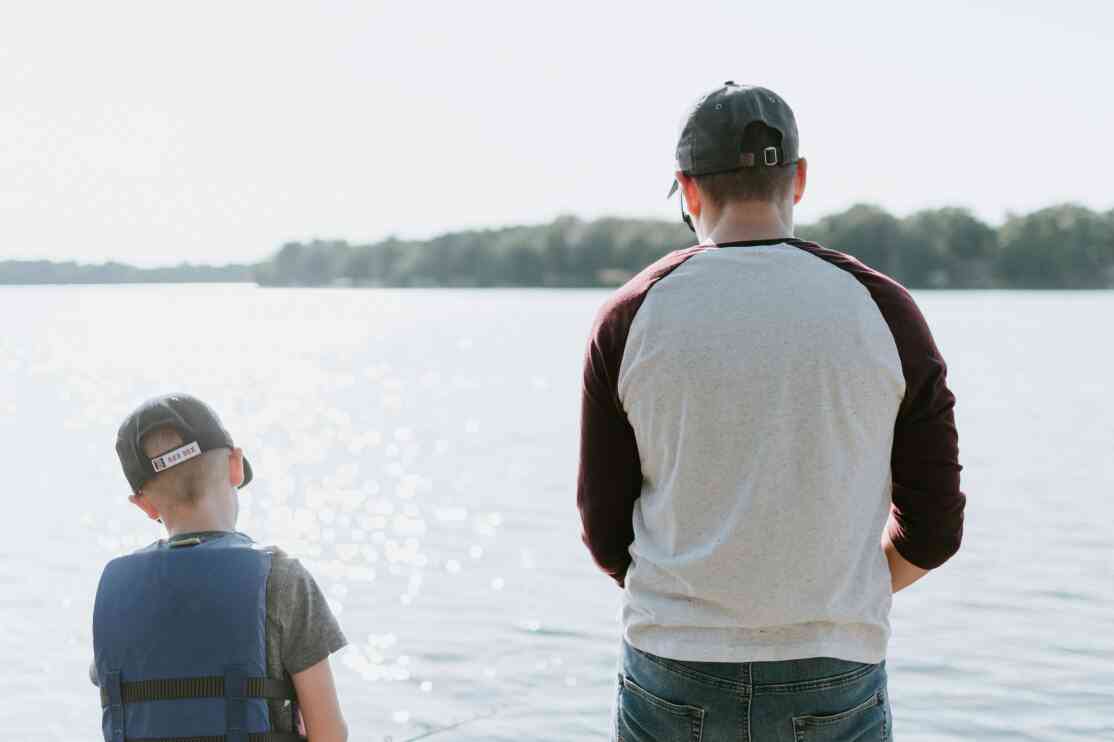 Photo of child with adult by a lake