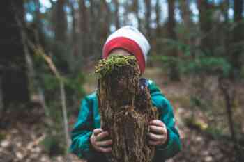 Child hiding behind mossy log